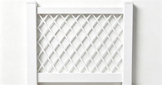 White vinyl full diamond lattice fence panel, diagonal slats forming diamond openings, two square posts, framed border, white background