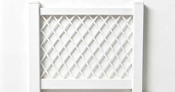 White vinyl full diamond lattice fence panel, diagonal slats forming diamond openings, two square posts, framed border, white background